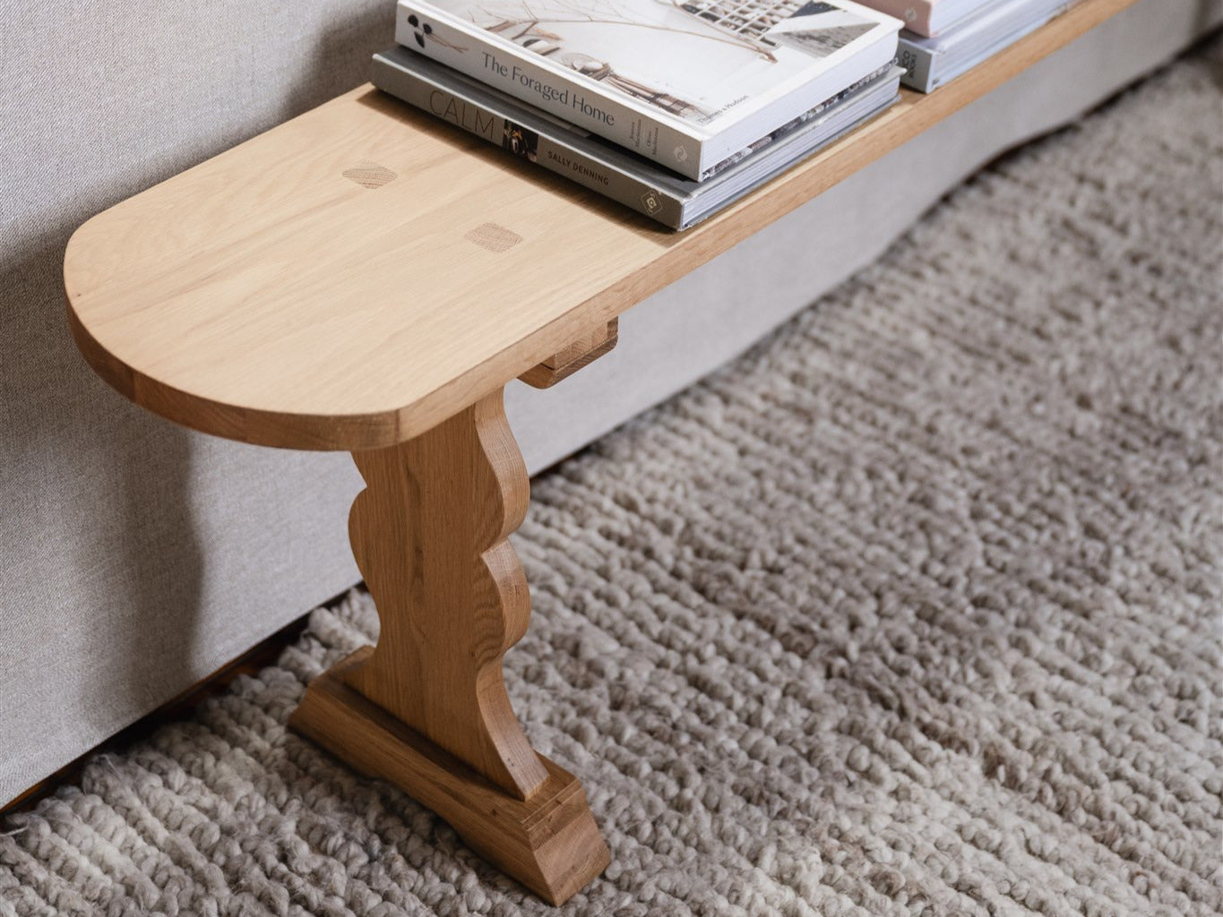 The versatile french bench with books on it at the end of a couch designed for its versatility. 